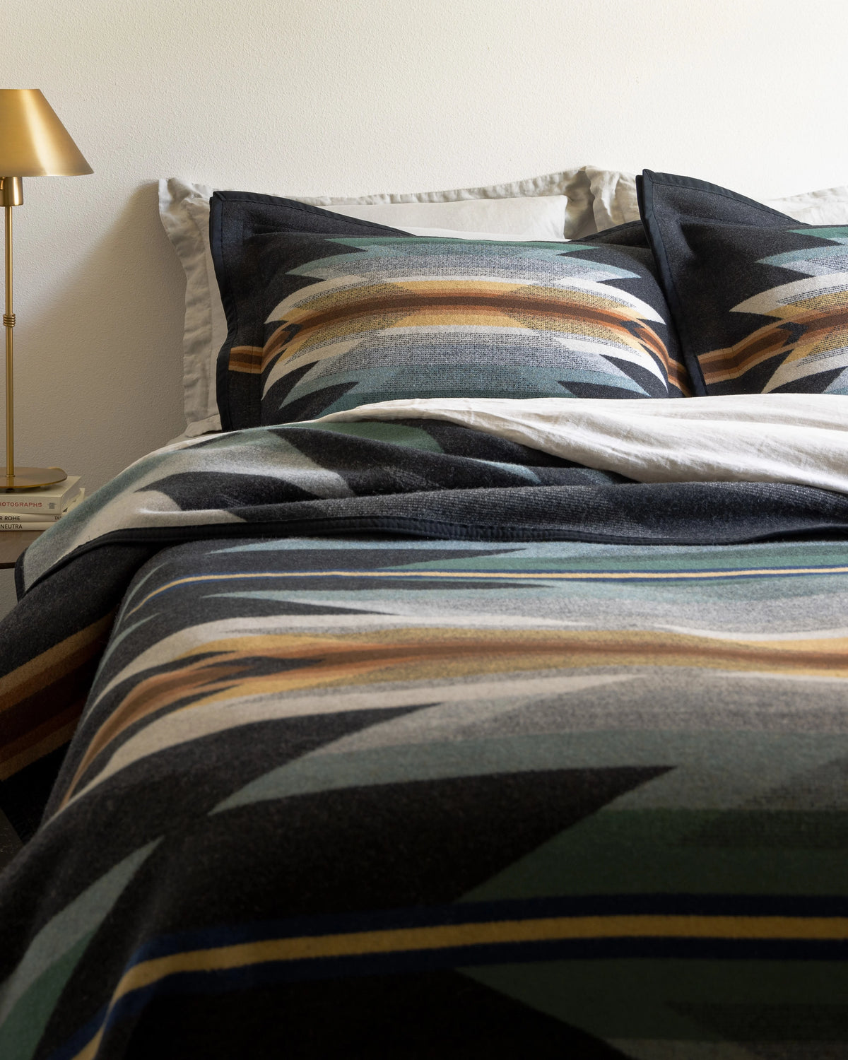 Patterned bedding set on a bed with a lamp on the side table next to the bed