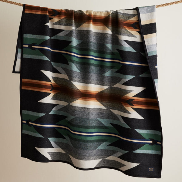 Patterned blanket with geometric design draped over a rope